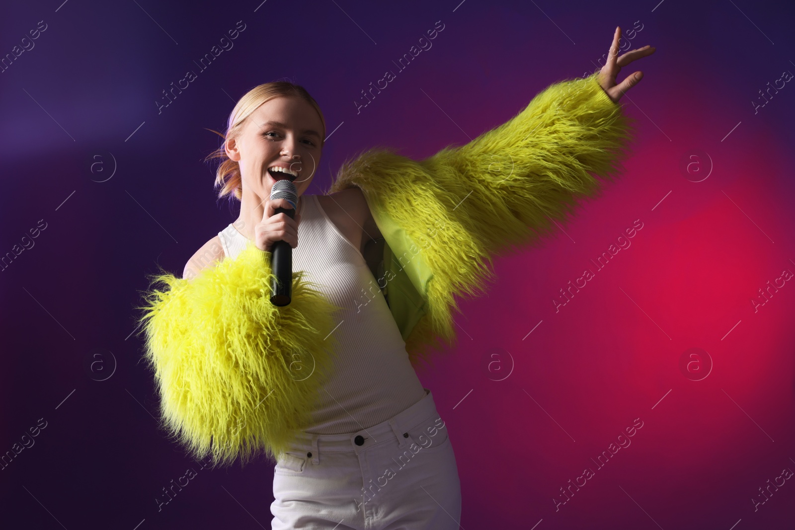 Photo of Talented singer in faux fur performing on purple background with pink light