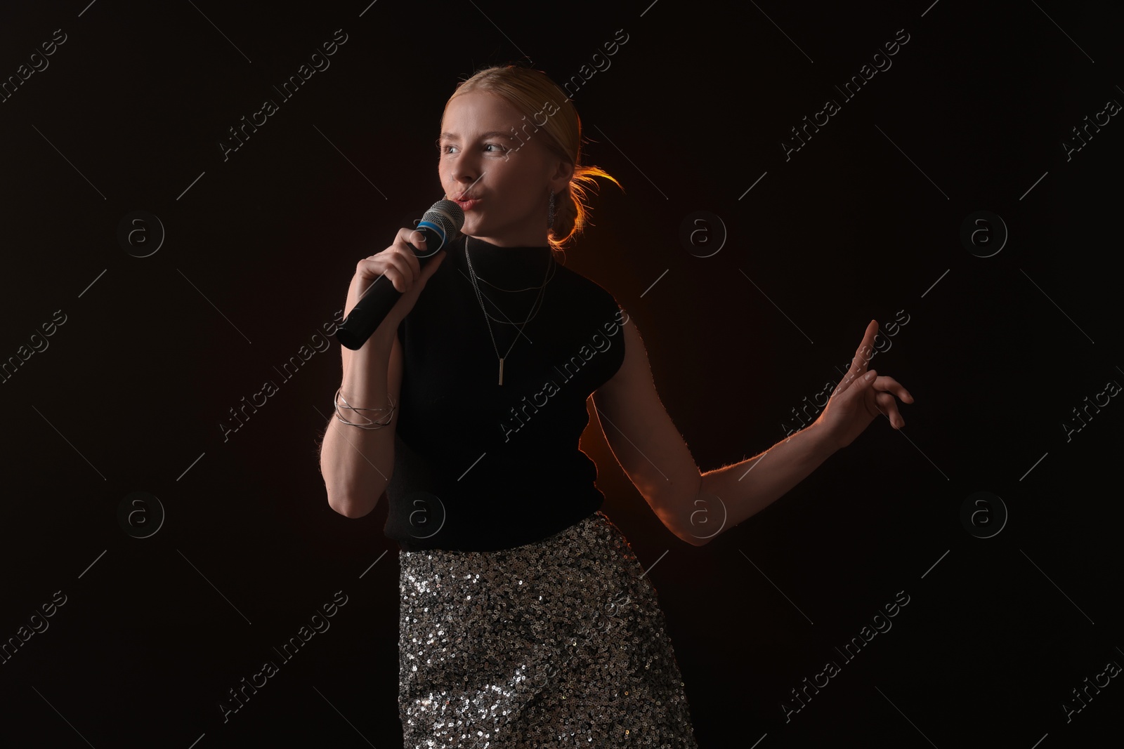 Photo of Beautiful talented singer performing on dark background