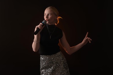 Photo of Beautiful talented singer performing on dark background