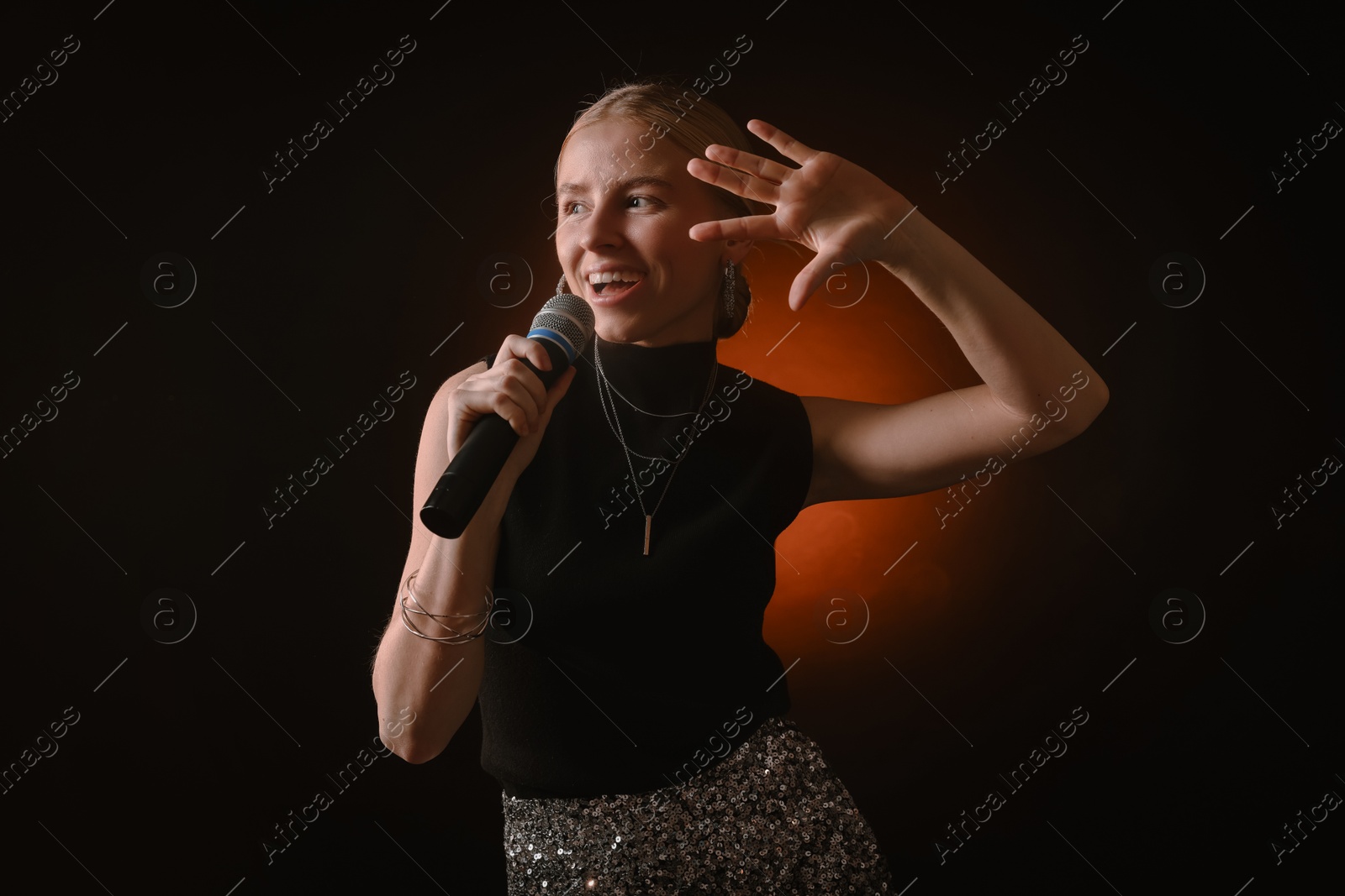 Photo of Beautiful singer performing on dark background with color light