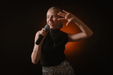 Photo of Beautiful singer performing on dark background with color light