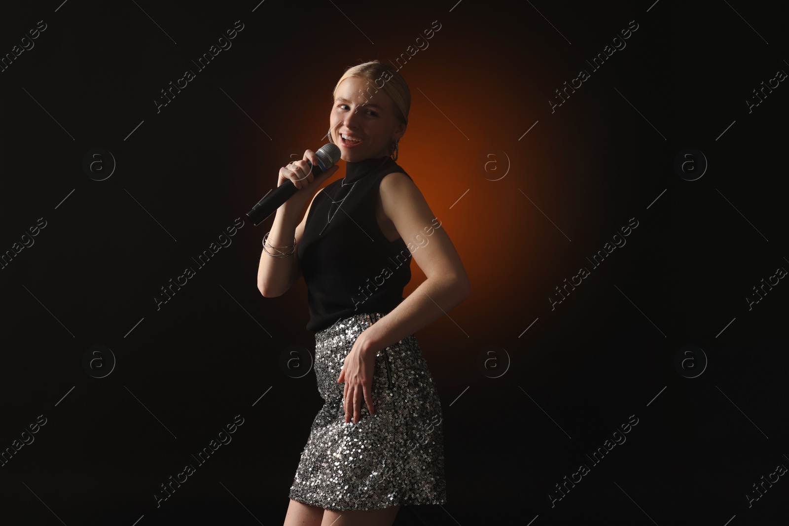 Photo of Beautiful singer performing on dark background with color light