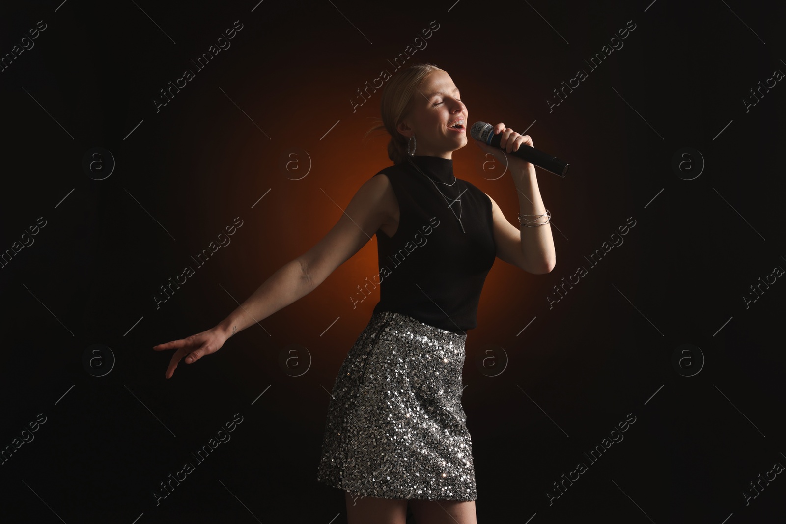 Photo of Beautiful singer performing on dark background with color light