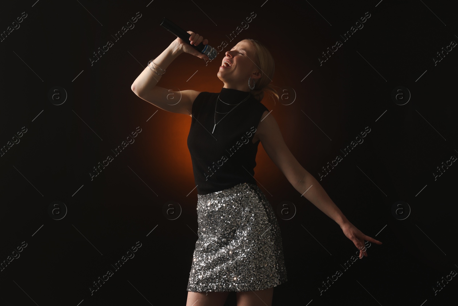 Photo of Beautiful singer performing on dark background with color light