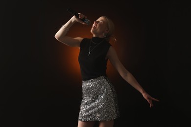 Photo of Beautiful singer performing on dark background with color light