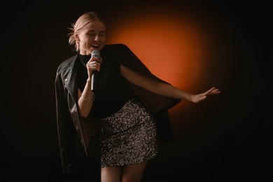 Photo of Beautiful singer performing on dark background with color light