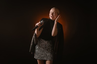 Photo of Beautiful singer performing on dark background with color light