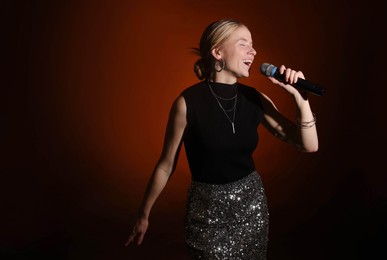 Photo of Beautiful singer performing on dark background with color light