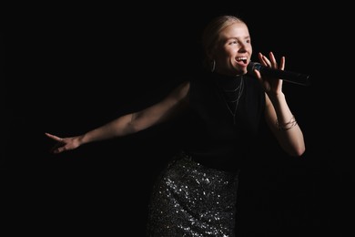 Photo of Beautiful talented singer performing on black background