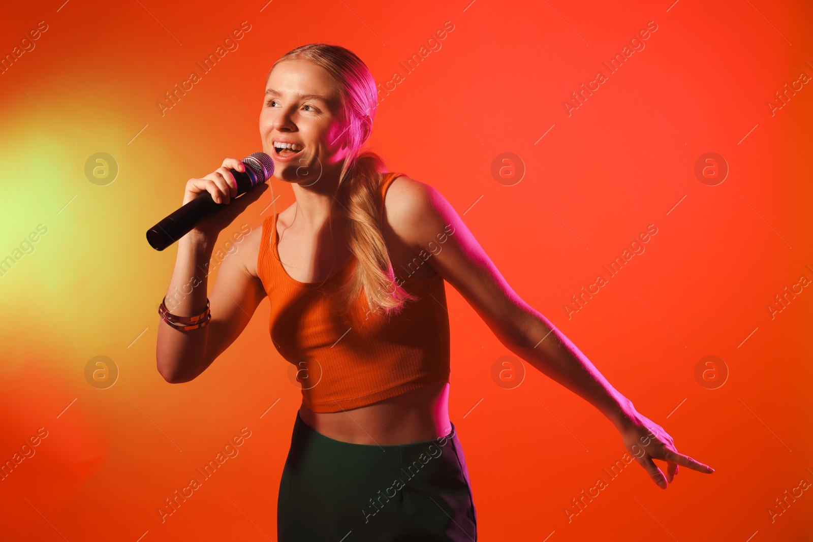 Photo of Talented singer performing on red background with yellow light. Space for text