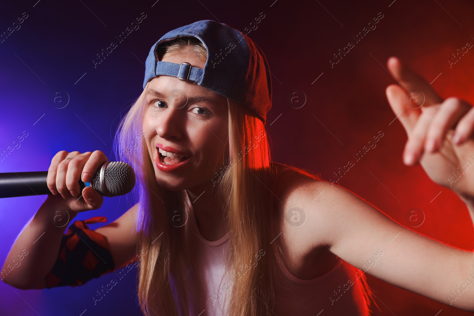 Photo of Talented singer performing on dark background with color lights