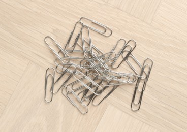 Photo of Many metal paper clips on wooden table, top view