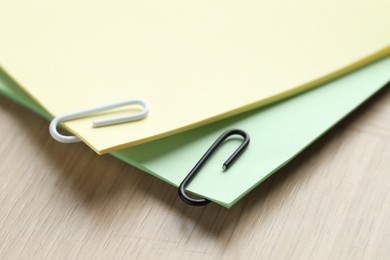 Photo of Paper notes with clips on wooden table, closeup