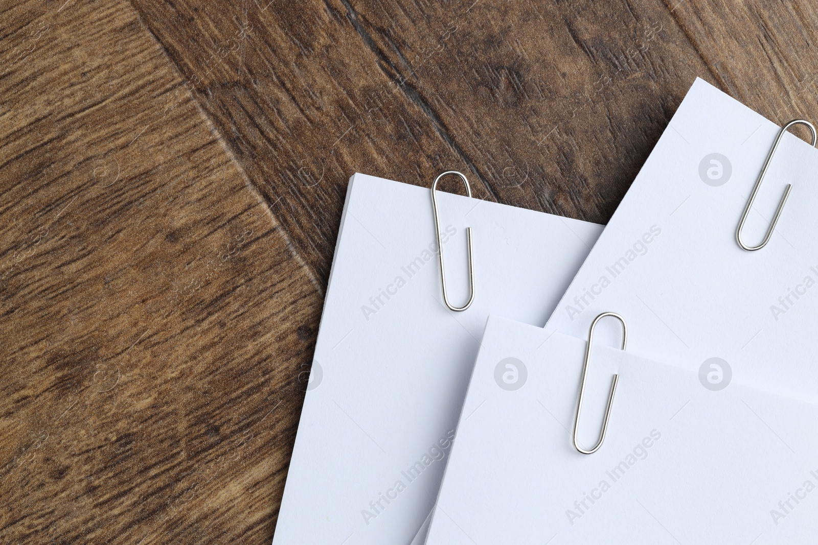 Photo of Paper notes with clips on wooden table, top view. Space for text