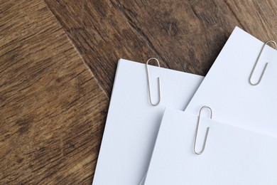 Photo of Paper notes with clips on wooden table, top view. Space for text