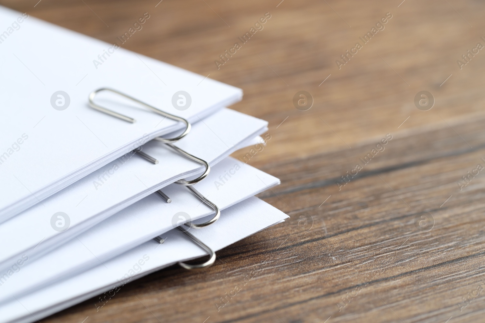 Photo of Paper notes with clips on wooden table, closeup. Space for text