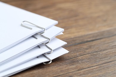 Photo of Paper notes with clips on wooden table, closeup. Space for text