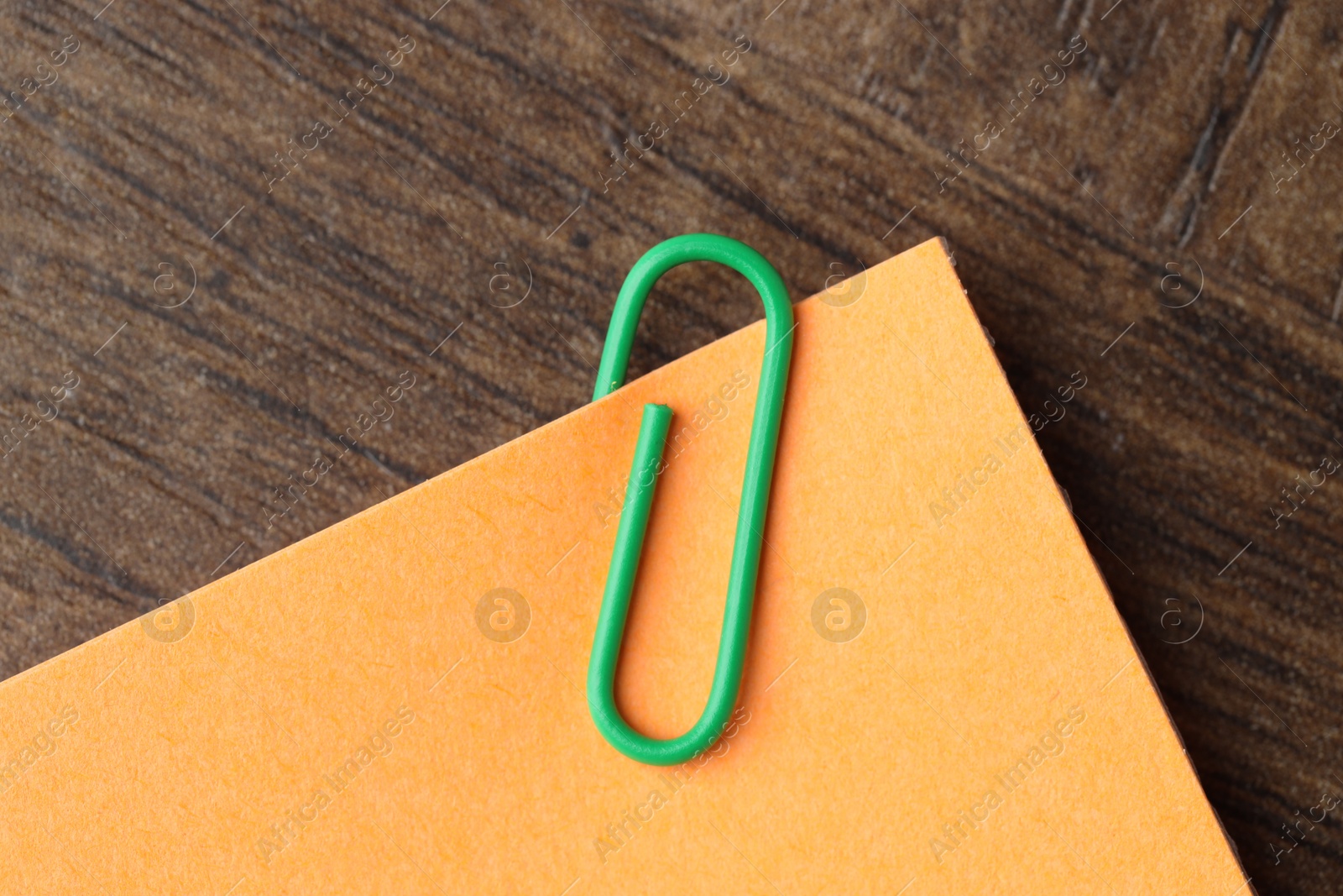 Photo of Paper note with clip on wooden table, top view