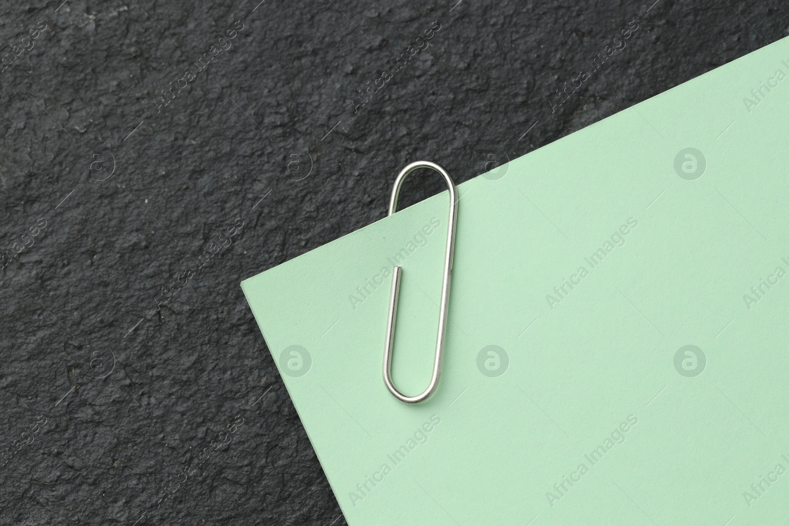 Photo of Paper note with clip on black table, top view. Space for text