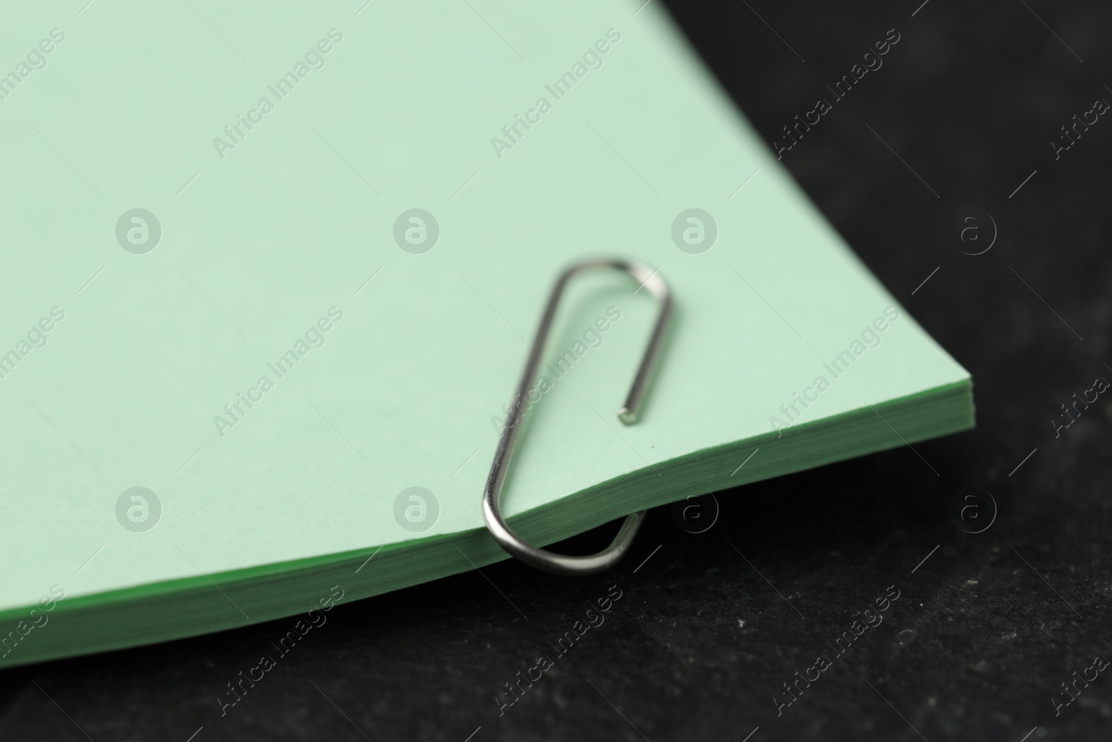 Photo of Paper notes with clip on black table, closeup