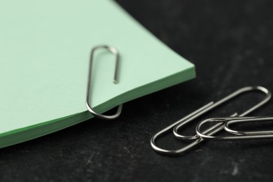 Photo of Paper notes and clips on black table, closeup