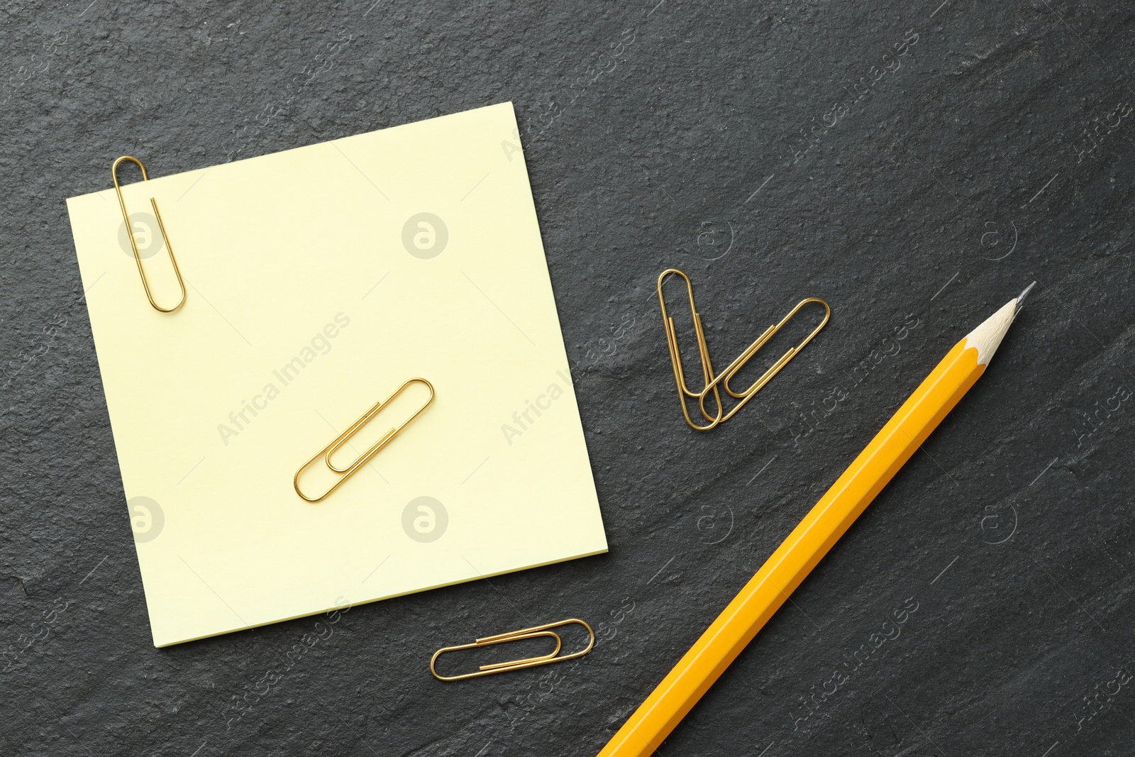 Photo of Paper notes, pencil and clips on black table, flat lay