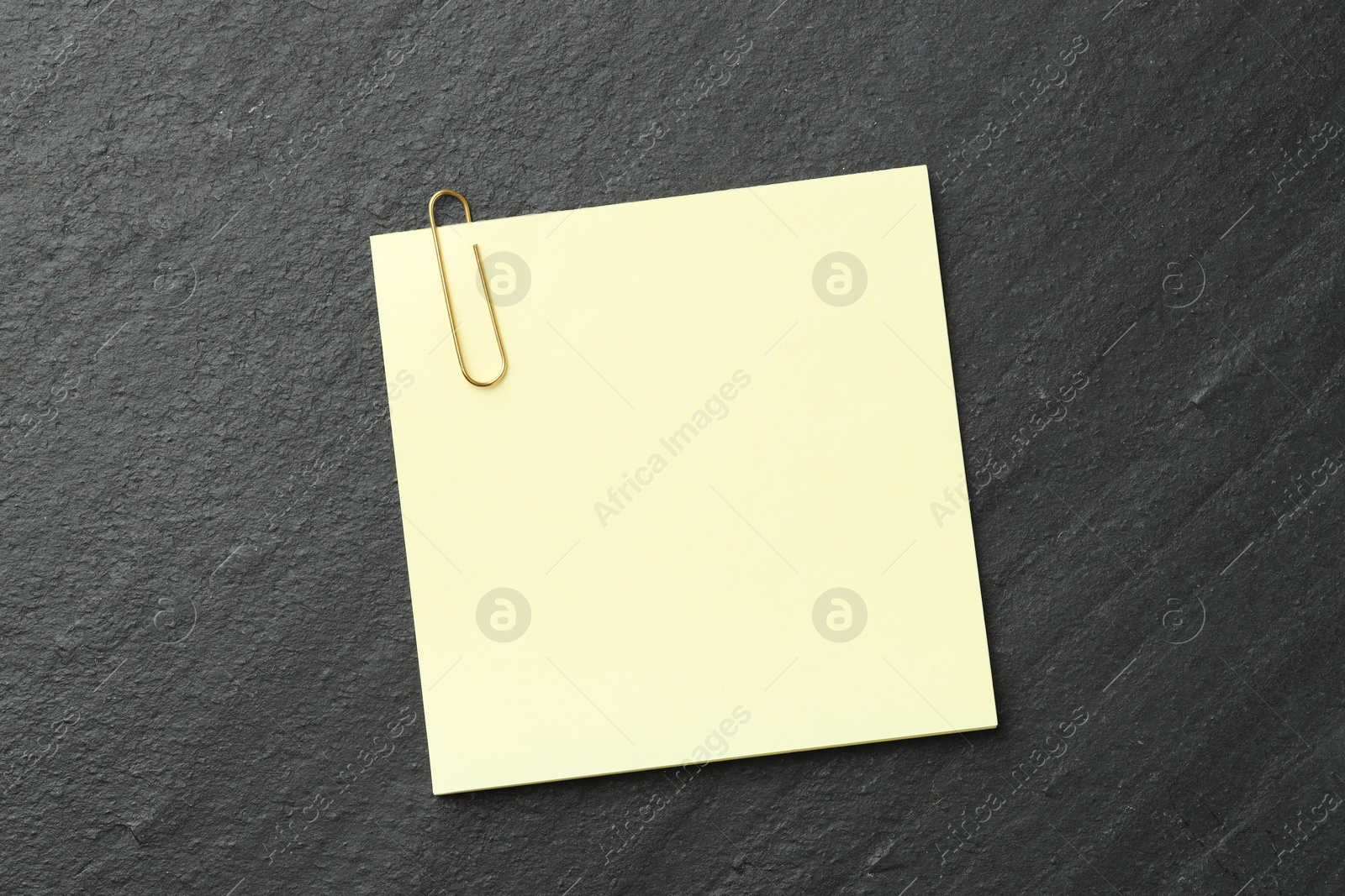 Photo of Paper notes with clip on black table, top view. Space for text