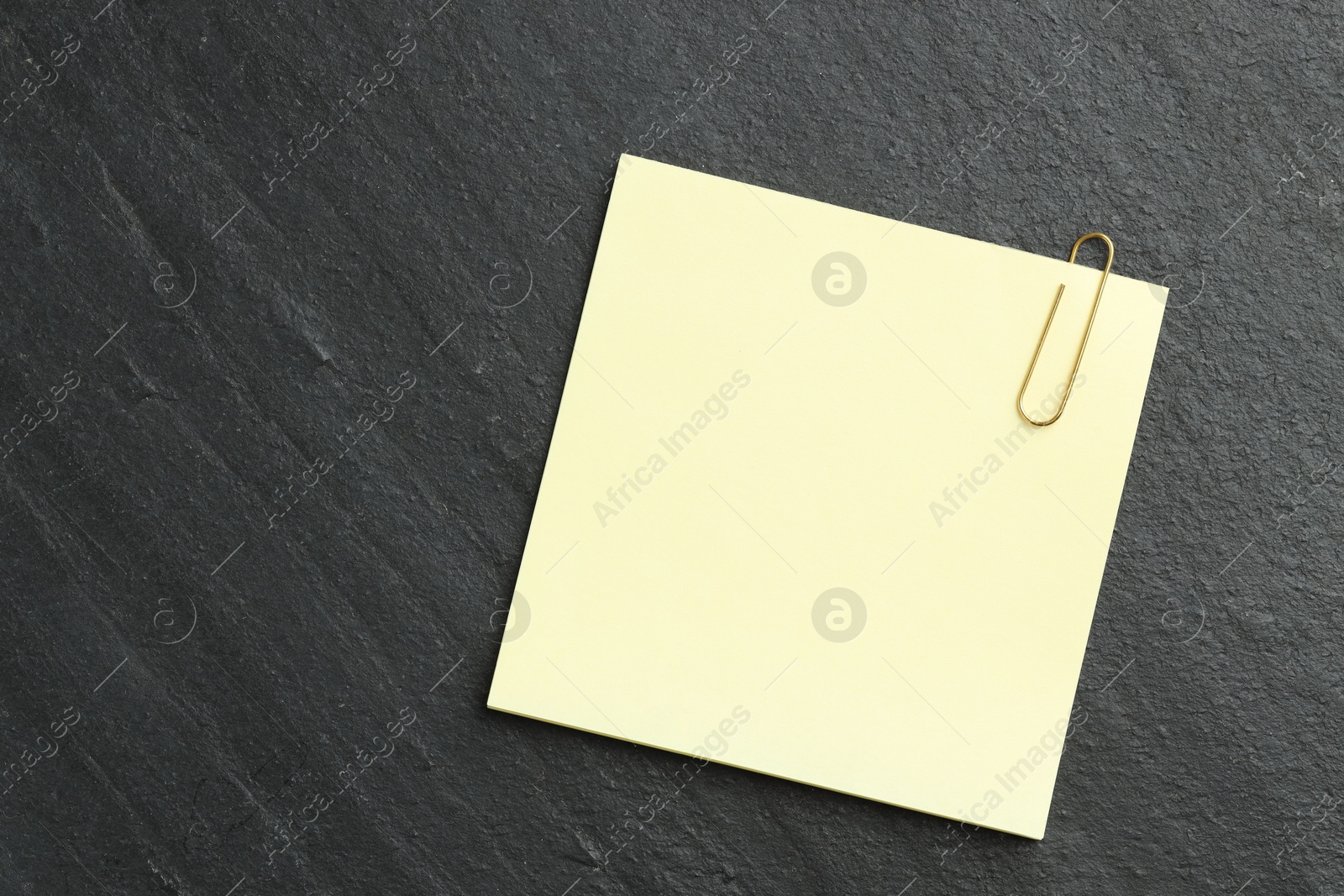 Photo of Paper notes with clip on black table, top view. Space for text