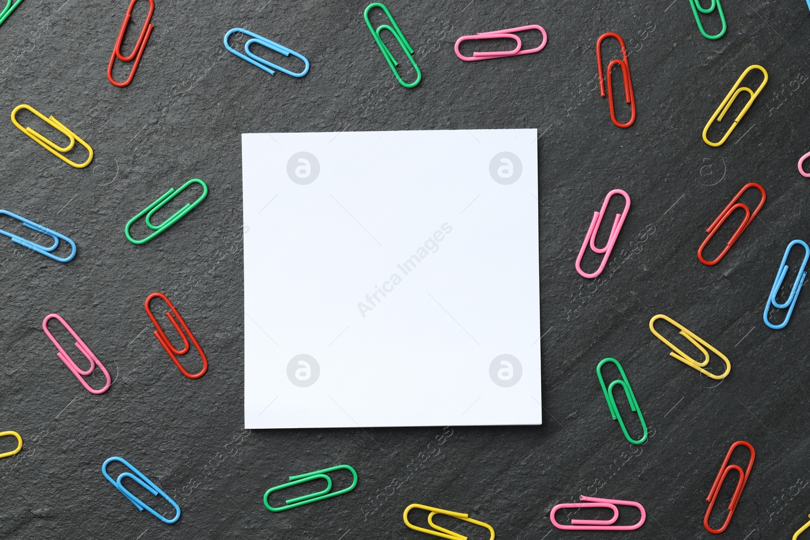 Photo of Paper note and colorful clips on black table, flat lay. Space for text