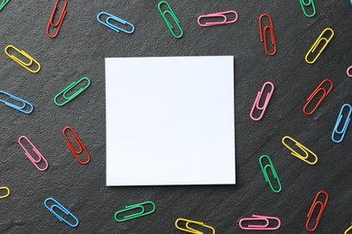 Photo of Paper note and colorful clips on black table, flat lay. Space for text