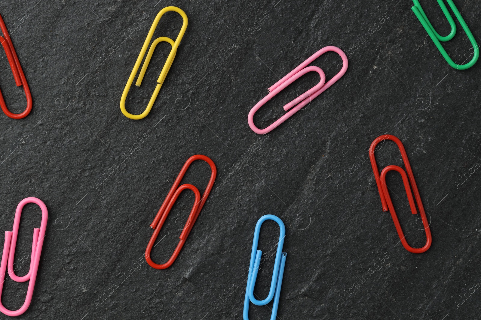 Photo of Many colorful paper clips on black table, flat lay