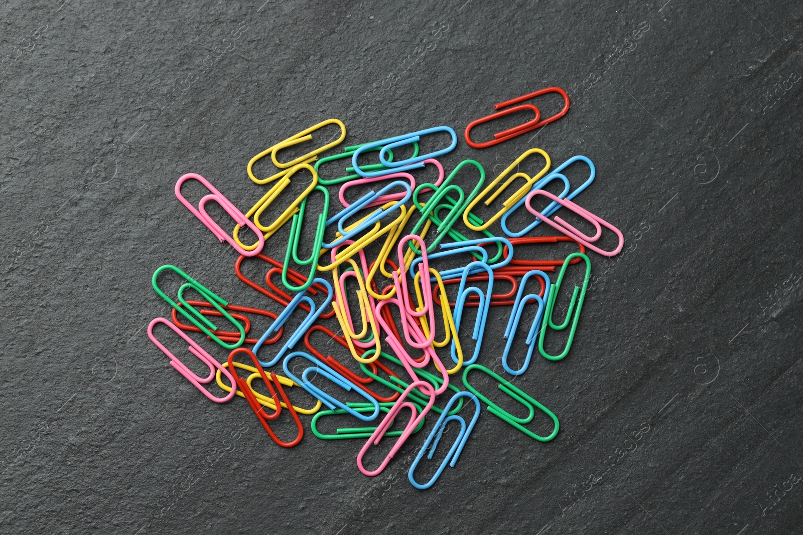 Photo of Many colorful paper clips on black table, top view