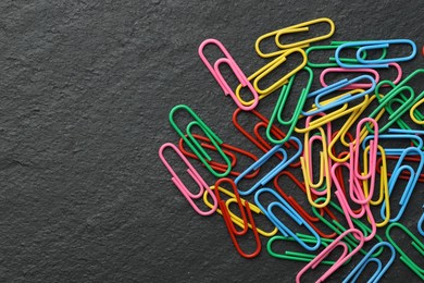 Photo of Many colorful paper clips on black table, top view. Space for text