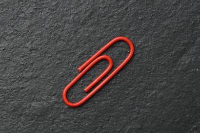 Photo of One red paper clip on black table, top view