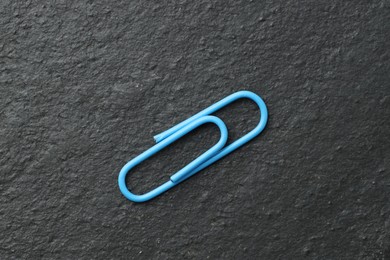 Photo of One blue paper clip on black table, top view