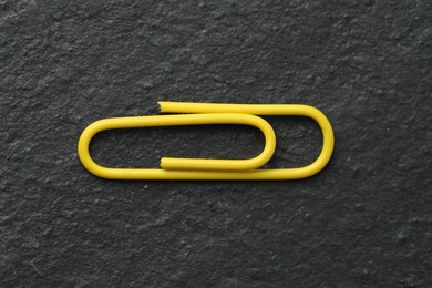 Photo of One yellow paper clip on black table, top view