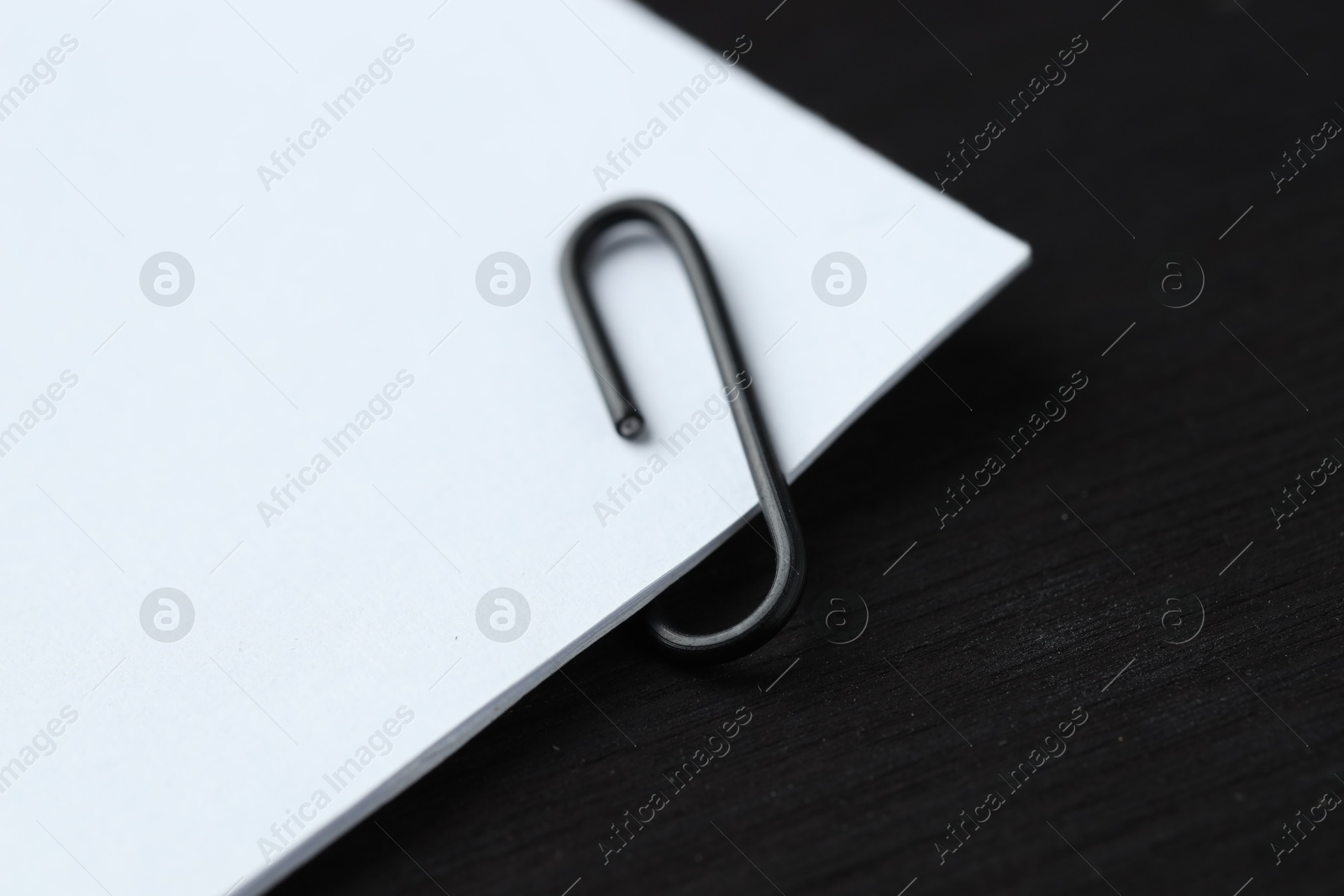 Photo of Paper notes with clip on black wooden table, closeup. Space for text