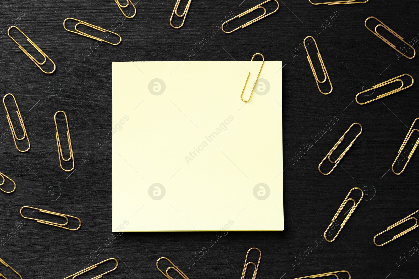 Photo of Paper notes and many golden clips on black wooden table, flat lay