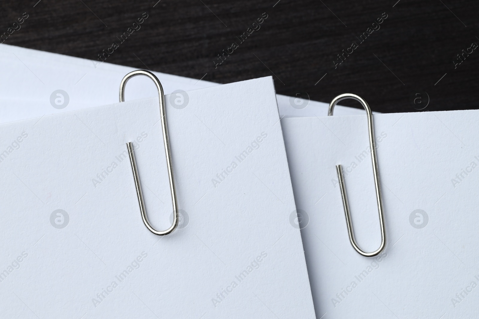 Photo of Paper notes with metal clips on black wooden table, top view