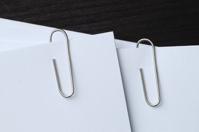 Photo of Paper notes with metal clips on black wooden table, top view