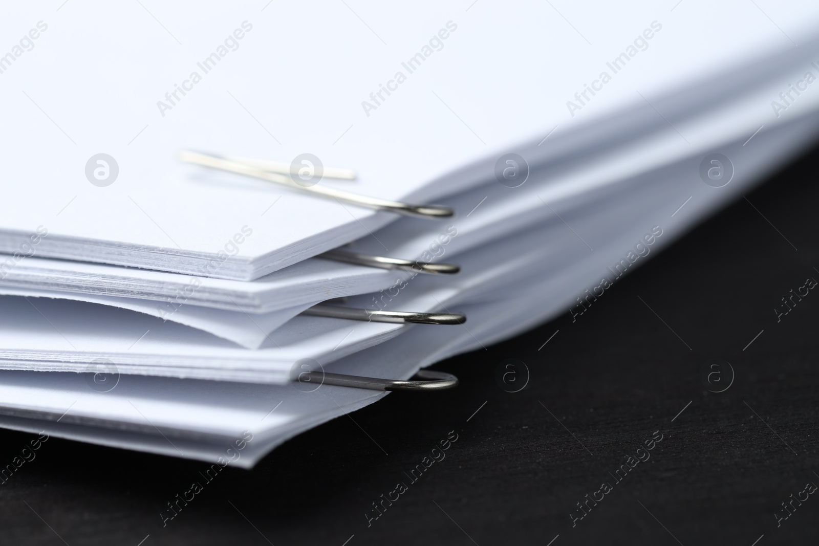 Photo of Paper notes with metal clips on black wooden table, closeup