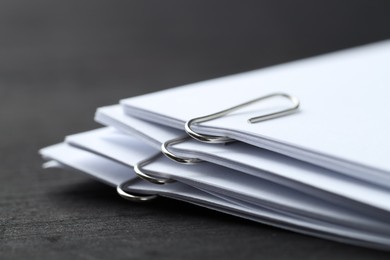 Photo of Paper notes with metal clips on black wooden table, closeup