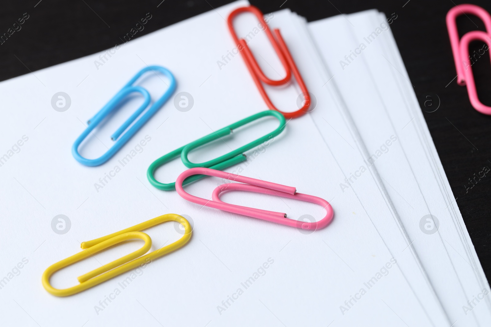 Photo of Many colorful clips and paper notes on black wooden table, closeup