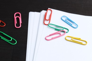 Photo of Many colorful clips and paper notes on black wooden table, closeup