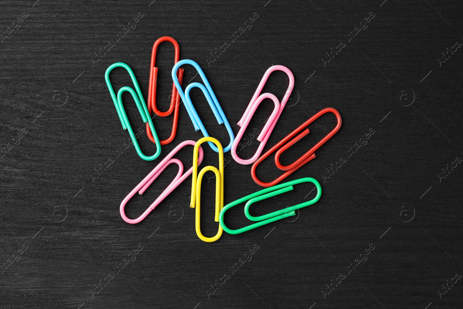 Photo of Many colorful paper clips on black wooden table, top view