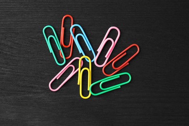 Photo of Many colorful paper clips on black wooden table, top view