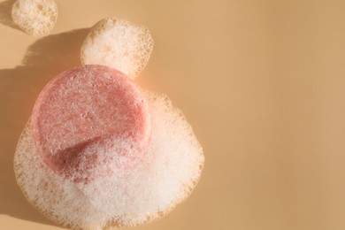 Photo of Soap bar with foam on peach background, top view. Space for text