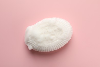 Photo of Soap bar with foam on light pink background, top view