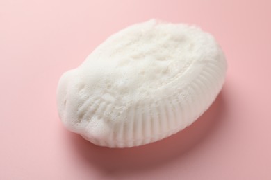 Photo of Soap bar with foam on light pink background, closeup