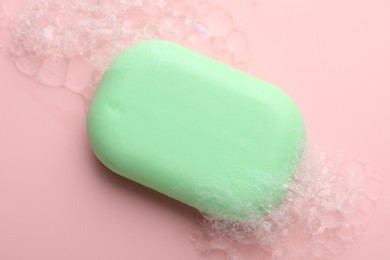 Photo of Soap bar with foam on light pink background